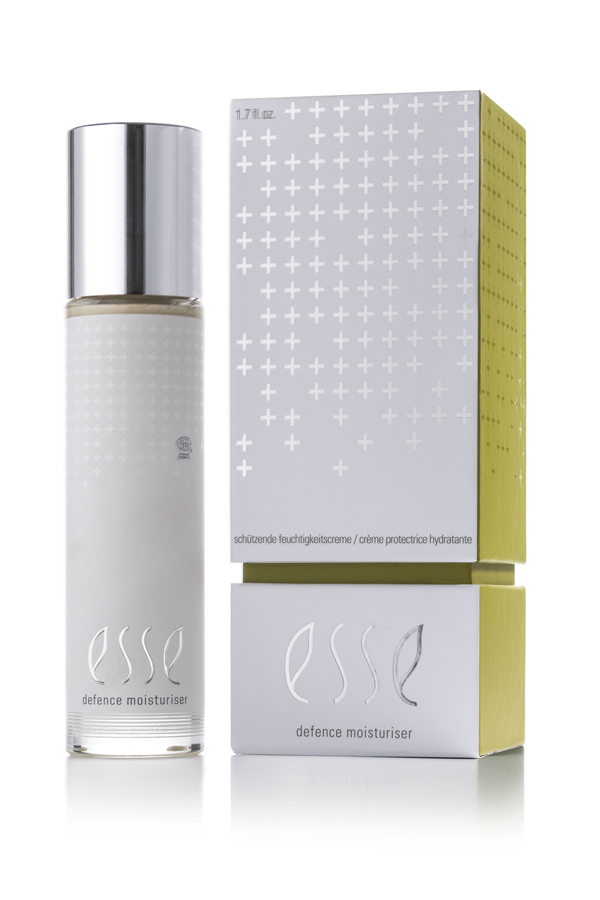 A bottle of Esse Defence Moisturiser is placed beside its box, both showcasing a sleek silver and white design with cross patterns and minimalist branding.