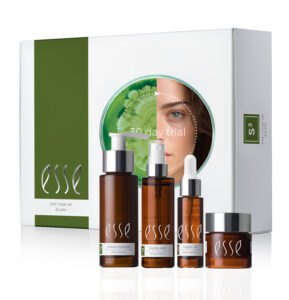 The Esse Sensitive Skin Trial/Travel Set includes a cream cleanser in a pump bottle, a toner in a spray bottle, a repair oil with a dropper, and a nourishing moisturizer in a jar, all displayed in front of a white and green box featuring an illustrated woman's face.