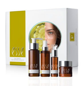 A white box labeled "20 day trial" with a circular cutout reveals part of a woman's face and a green botanical image. In front of the box are four brown skincare bottles with white labels, including a gel cleanser, hydrating cream, serum, and eye cream, all branded with "Esse" from the Esse Oily / Combination / Normal Trial / Travel Set.